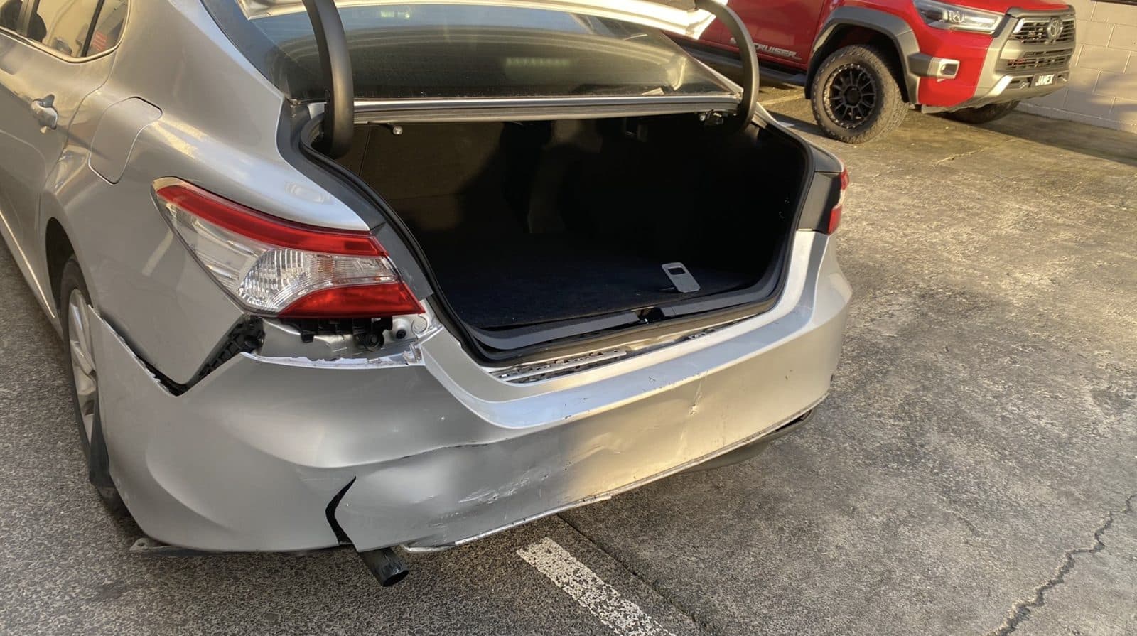 Crushed rear end and open boot on a silver Toyota Camry before repair