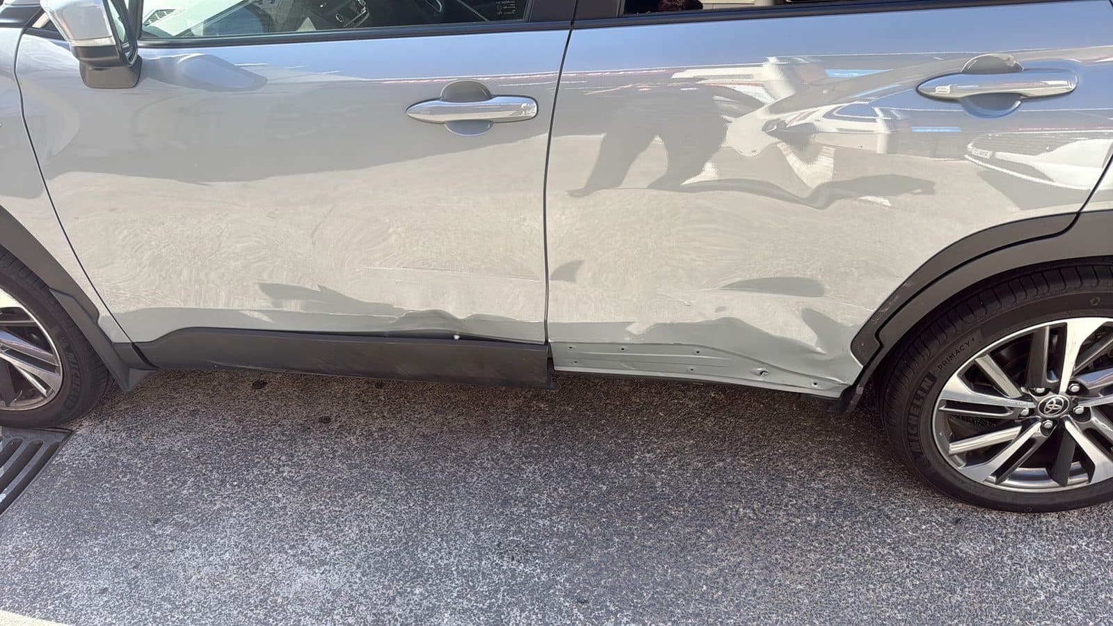 Dented doors along the side of a silver Toyota Corolla Cross before repair