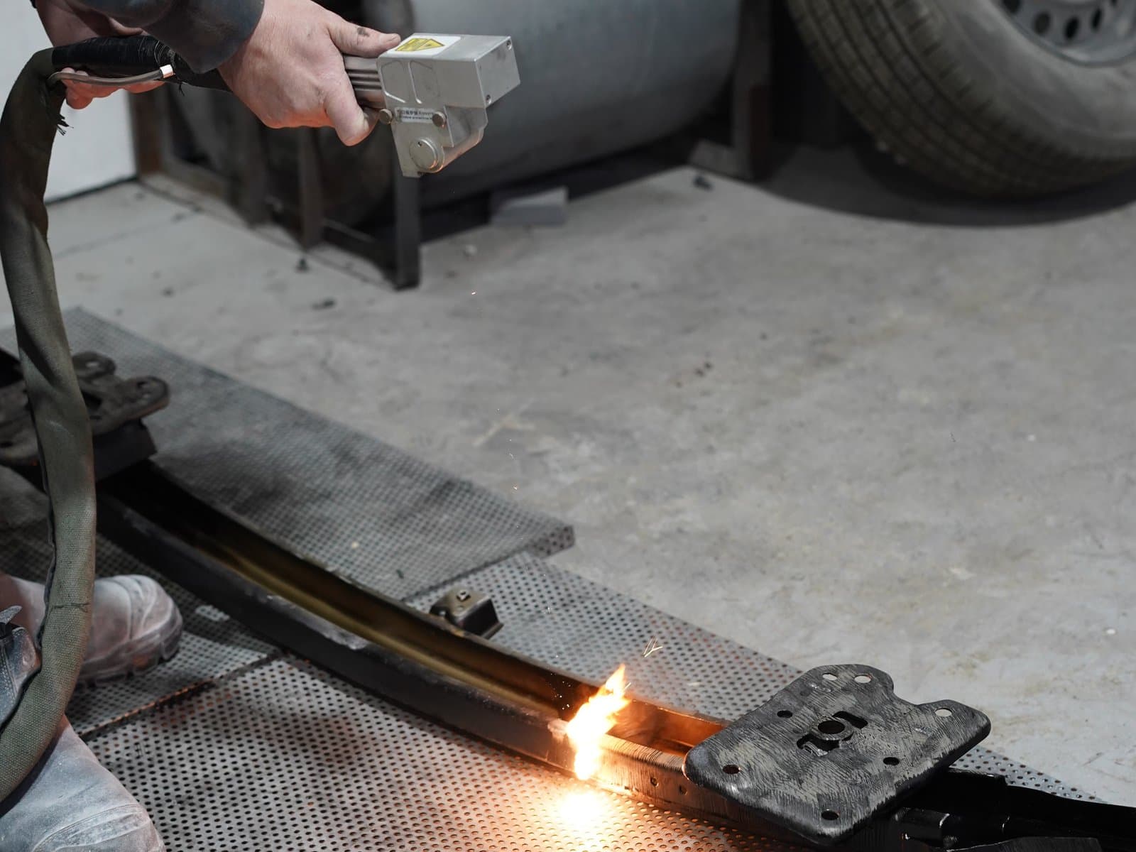 Technician's laser gun cutting rust from a leaf spring with a bright flame